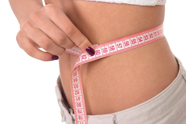 Isolated slim girl with centimeter on a white surface