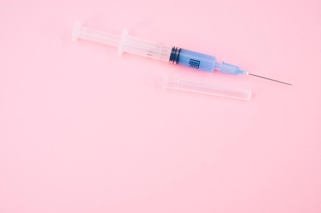 Isolated sterilized injection syringe on a pink background