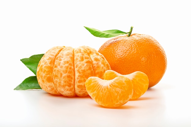 Photo isolated tangerines. half of peeled tangerine and whole mandarin or orange fruit with green leaves isolated on white background. close up.