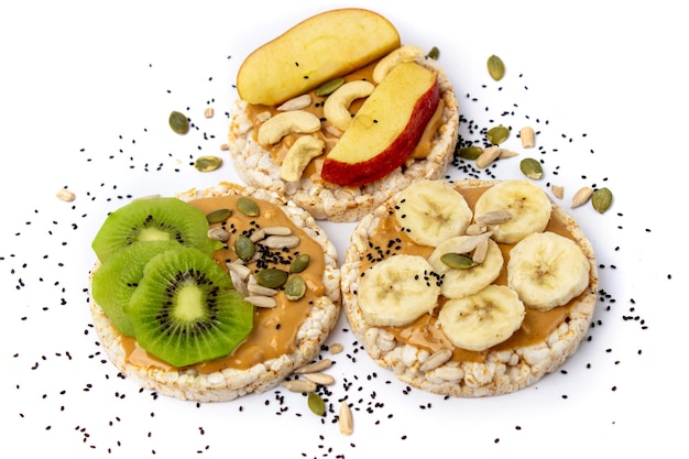 Isolated three healthy rice cake meal with peanut butter kiwi slice banana seeds and apple