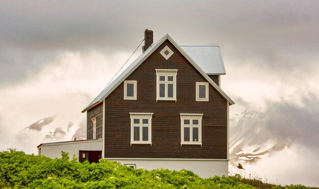 Фото Изолированный двухэтажный дом в горах исландского острова со снегом на заднем плане