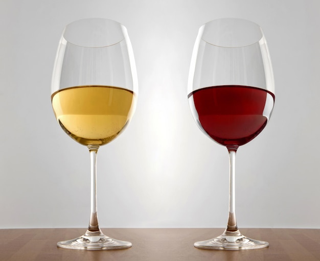 Photo isolated white and red wine glasses on wooden table