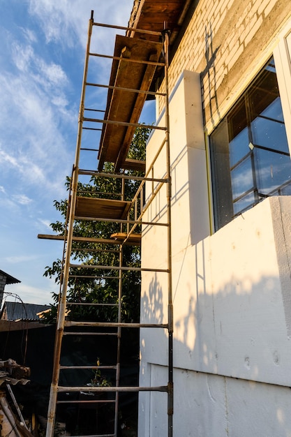 Isolatie van het huis met piepschuim. Steiger op gebouw