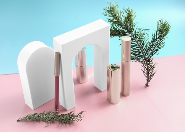 Foto isometrische set cosmetische producten met kerstboomtak lippenstift mascara en lipliner met boogpodium merkloze vakantiecadeaus voor vrouwen op blauwe en roze achtergrond