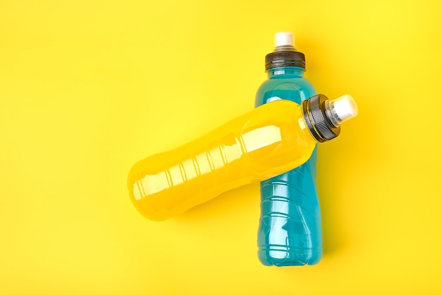 Isotonic energy yellow and blue sport drink in plastic bottles on yellow background allows to