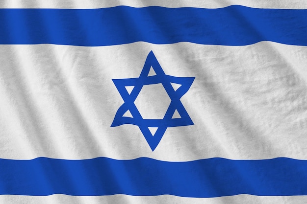 Israel flag with big folds waving close up under the studio light indoors The official symbols and colors in banner