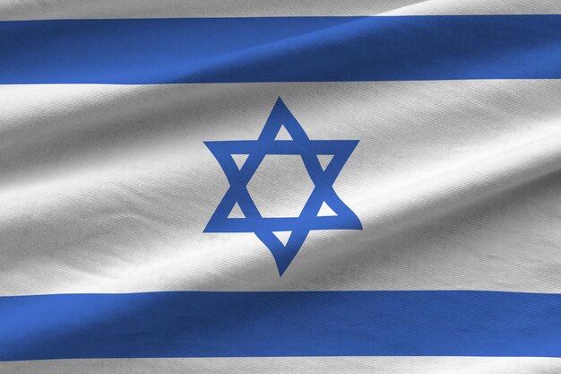 Israel flag with big folds waving close up under the studio light indoors The official symbols and colors in banner