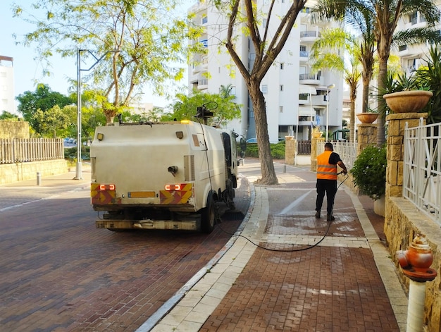 Israëlische arbeider wast straatstenen met een tuinslang tijdens het rijden op de weg Achteraanzicht