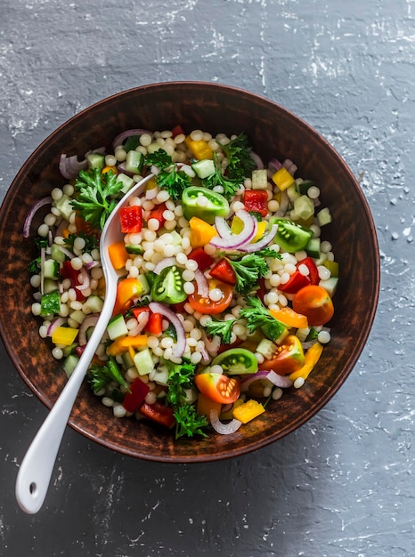 Israëlische couscous ptitim groenten tabouleh salade op een grijze achtergrond bovenaanzicht