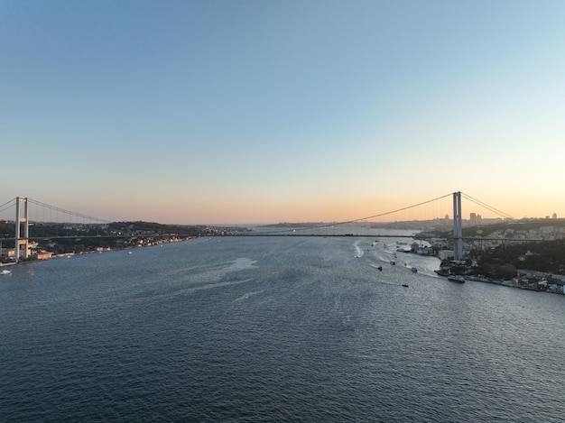 イスタンブール・ボスフォラス橋と背景の都市スカイラインとトルコ国旗の美しい夕暮れ 空中スライド軌道とトラッキングショット