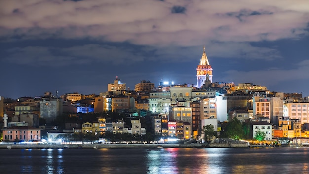 Paesaggio urbano di istanbul con la torre di galata e barche turistiche galleggianti nella notte del bosforo