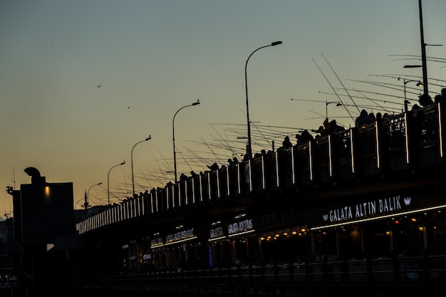 Istanbul Turkey December 04 2015 Fishermen silhouette over Galata bridge reverse light image