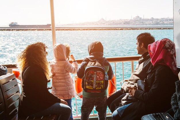 Istanbul, Turkije - 31 maart 2017: Jonge Turkse familie genieten van uitzicht op zee op de Bosporus, uitzicht vanaf de achterkant met kinderen op de veerboot. Istanbul is een romantische en interessante reisbestemming met moskeeën