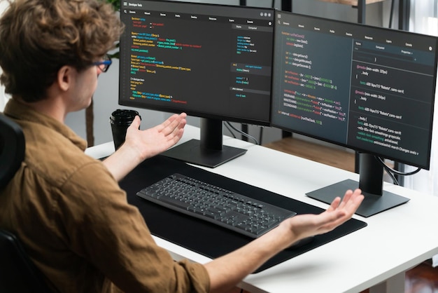 IT developer working online software development on pc monitors at modern home office on coding application screens creating updated latest program firmware information version concept Gusher