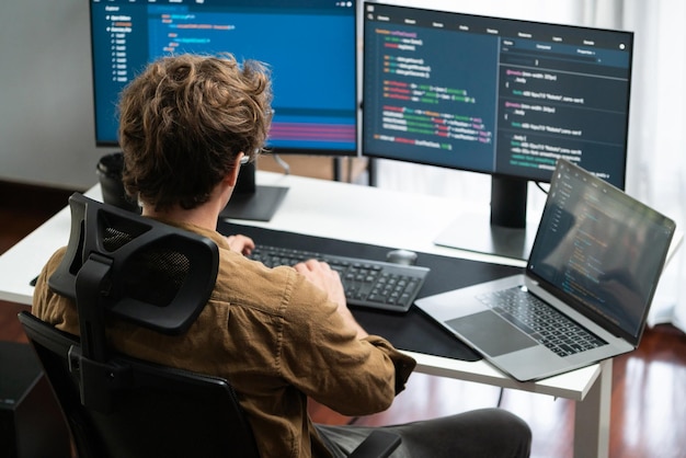 IT developer working online software development on pc monitors at modern home office on coding application screens creating updated latest program firmware information version concept Gusher