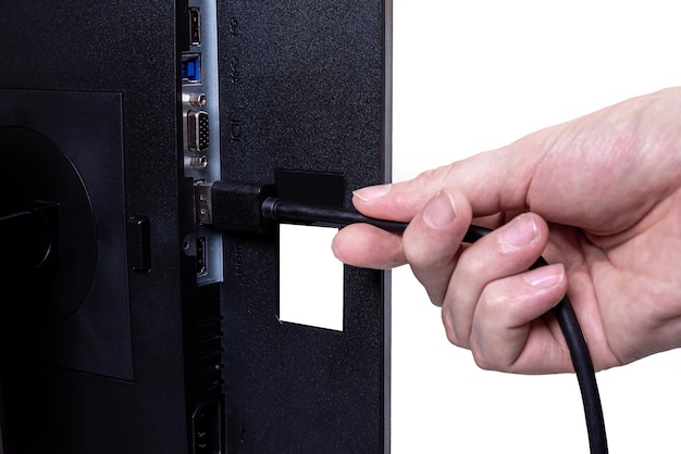 IT engineer Man hand inserts cable into monitor Man hand connecting the DVI cable for monitor to computer PC VGA DVI DisplayPort and power cable close up in the hands of an isolated