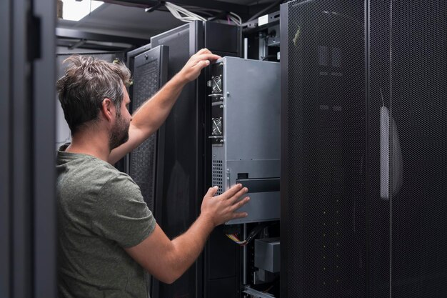 IT-ingenieur die in de serverruimte of het datacenter werkt. De technicus plaatst een nieuwe server van een corporate mainframe-supercomputer of een cryptocurrency-mijnbouwbedrijf in een rek.