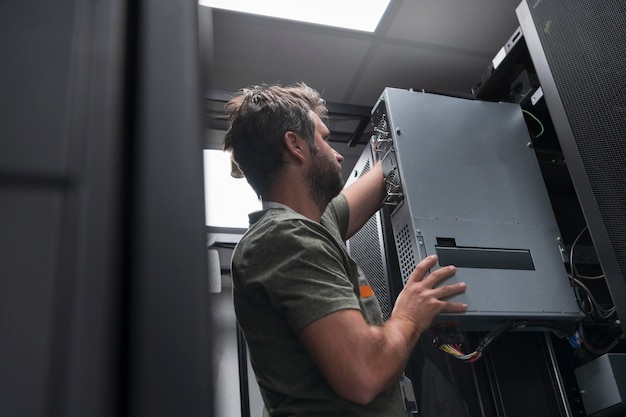 IT-ingenieur die in de serverruimte of het datacenter werkt. De technicus plaatst een nieuwe server van een corporate mainframe-supercomputer of een cryptocurrency-mijnbouwbedrijf in een rek.