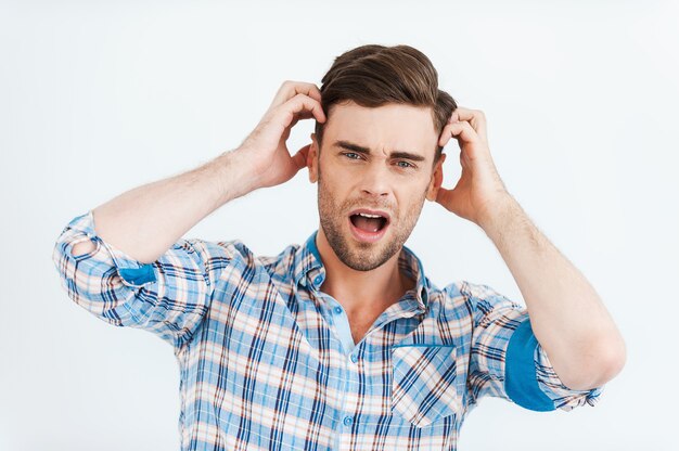 It is hard to believe! shocked young man in shirt holding head in hands