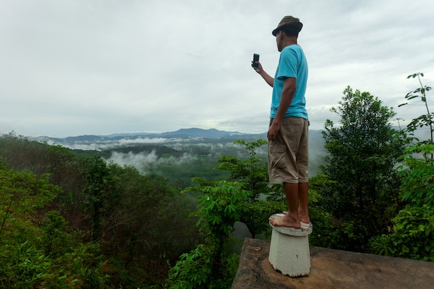 Photo it is selfie time in the nature landscape handsome young man holding smartphone making sel