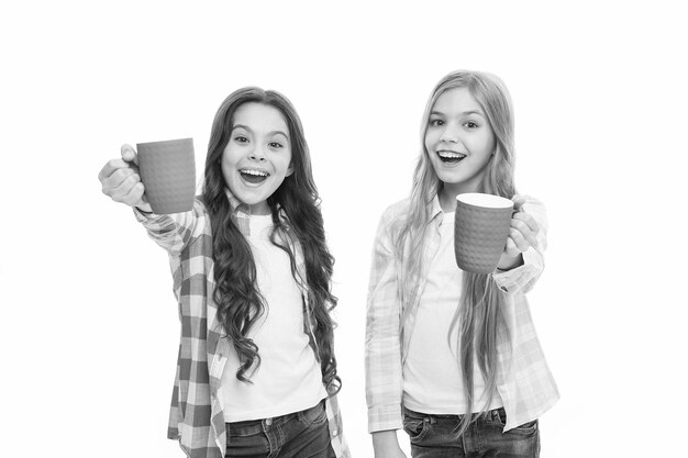 It is tea time Relaxing with drink Tea break Children do not drink enough during school day Make sure kids drink enough water Girls kids hold cups Sisters hold mugs Drinking tea while break