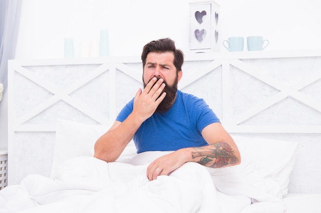 It is too early early morning getting the rest your body needs bed is so comfortable in morning peaceful mature male relaxing bearded man yawning in bed sleepy guy relax in bedroom