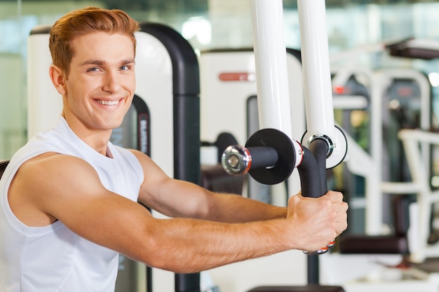 It is very important to stay fit. Handsome young man working out in gym and smiling