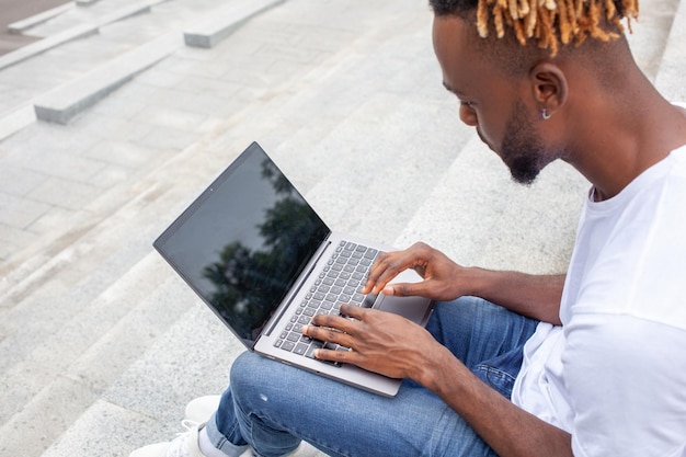 Foto it-ontwikkelaar afro-amerikaanse man aan het werk op laptop typen op toetsenbord zoeken naar informatie op het web