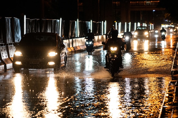 It rains on the city on streets with cars and motorcycles.