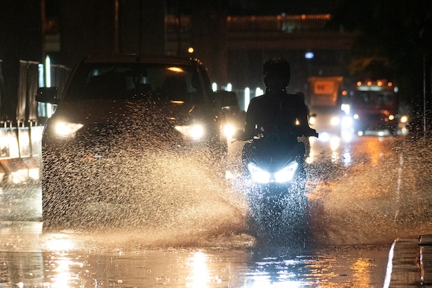 It rains on the city on streets with cars and motorcycles.