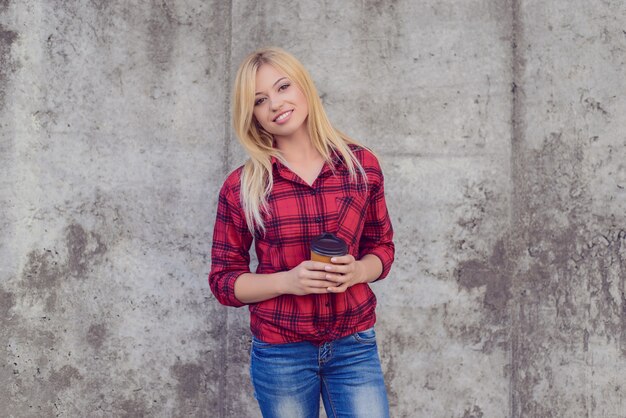 It's coffee time! Coffee time concept. Woman with beaming smile drinking coffee. Close up portrait, grey wall