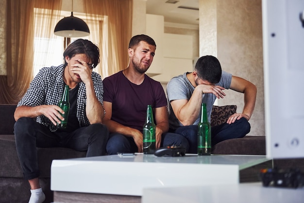 È una sconfitta. tre amici tristi che guardano insieme il calcio in tv a casa.