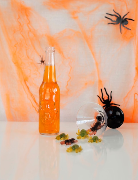 It's Halloween time. Bright colored drinks with sweets on the background of a spider web with cockroaches. A drink in a glass jar with a scary face. Selective focus.