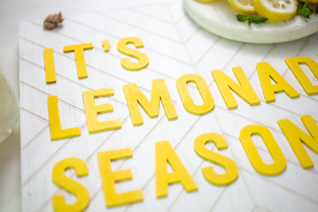 Это деревянный знак сезона лимонада со стаканом свежего лимонада.