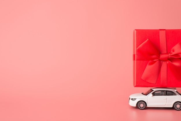 Photo it's shopping season concept. side profile close up view photo of mini modern car carrying giftbox on top roof isolated light color backdrop with copy space