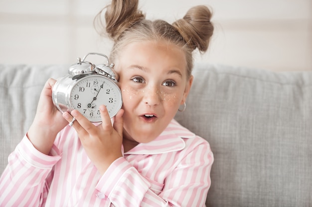 It`s time to wake up. Cute little girl with alarm clock