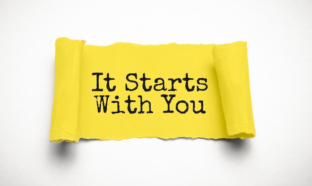 IT STARTS WITH YOU words text on yellow paper on torn paper background