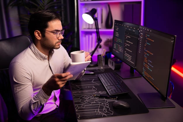 コーヒーを飲みPC画面でコーディングメモを読み推測する