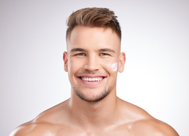 It works like a dream Studio shot of a young man applying moisturizer to his face against a grey background