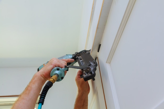 Do it yourself home owner repairing door frame molding with nail gun,