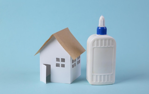 Do it yourself House model and glue bottle on blue background