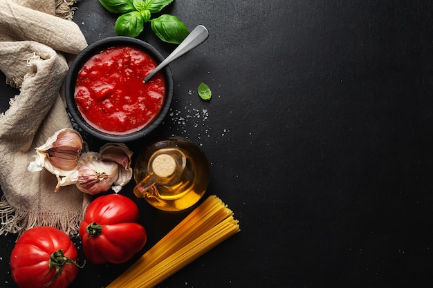 Italiaans eten achtergrond met spaghetti groenten en tomatensaus op donkere tafel. Bovenaanzicht.