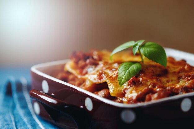 Foto italiaans eten heet smakelijke vers gebakken lasagne geserveerd met basilicum kruid close-up selectieve focus
