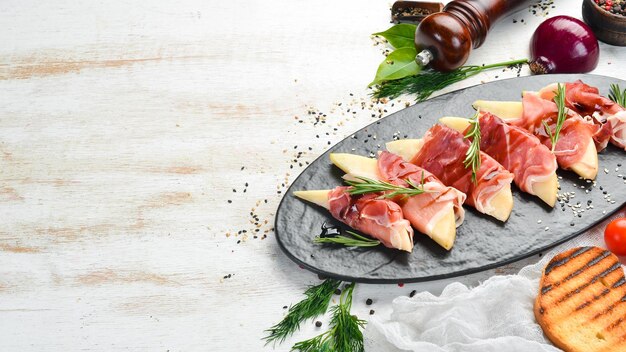 Italiaans eten Prosciutto met peer en balsamico saus Jamon op een zwarte stenen plaat Bovenaanzicht