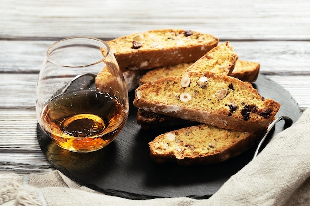 Foto italiaanse biscotti koekjes op zwart leisteenbord en zoete wijn vin santo vers gebakken koekjes met noten