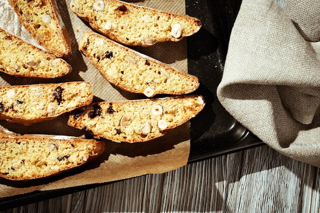 Italiaanse biscotti koekjes op zwarte bakplaat. Vers gebakken koekjes met noten en gedroogde veenbessen.