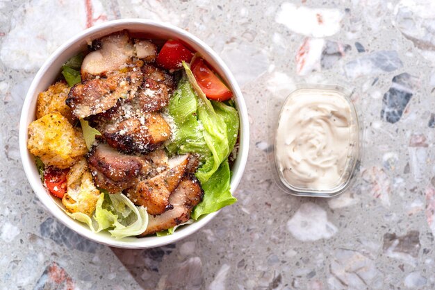 Italiaanse caesarsalade met parmezaanse kip en crackers in een ambachtelijke kartonnen container voor bezorging