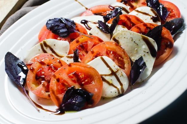 Italiaanse Caprese salade. Ingrediënten mozzarella kaas, tomaten, basilicum, zout, peper, balsamico.