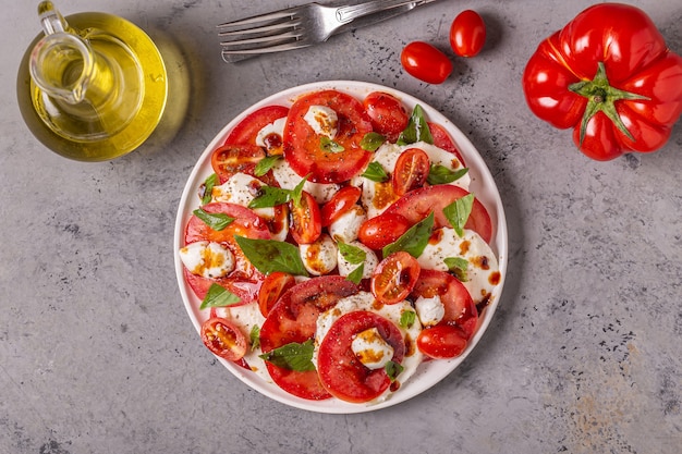 Italiaanse caprese salade met gesneden tomaten, mozzarella kaas, basilicum, olijfolie, balsamico azijn. Bovenaanzicht, kopieer ruimte.