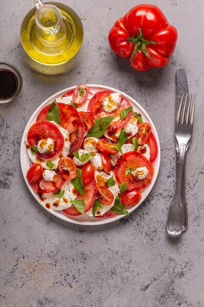 Italiaanse caprese salade met gesneden tomaten, mozzarella kaas, basilicum, olijfolie, balsamico azijn. Bovenaanzicht, kopieer ruimte.